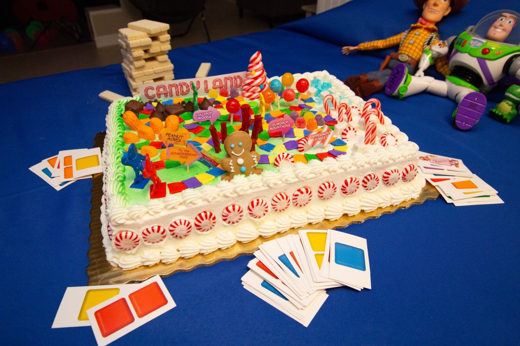Colorful Candyland-inspired birthday cake with gumdrops, peppermint candies, and Toy Story toys