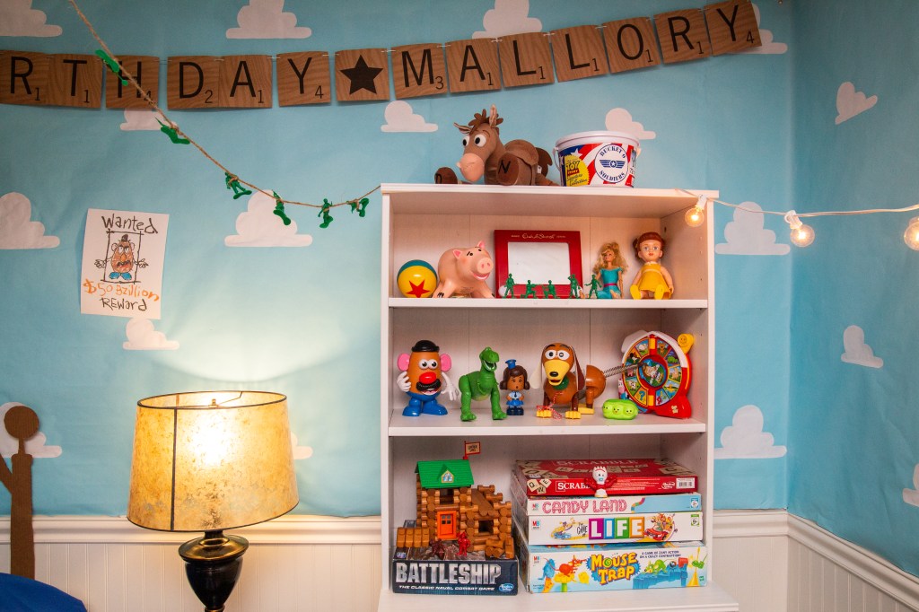White bookshelf styled with Toy Story characters and classic board games for party decor