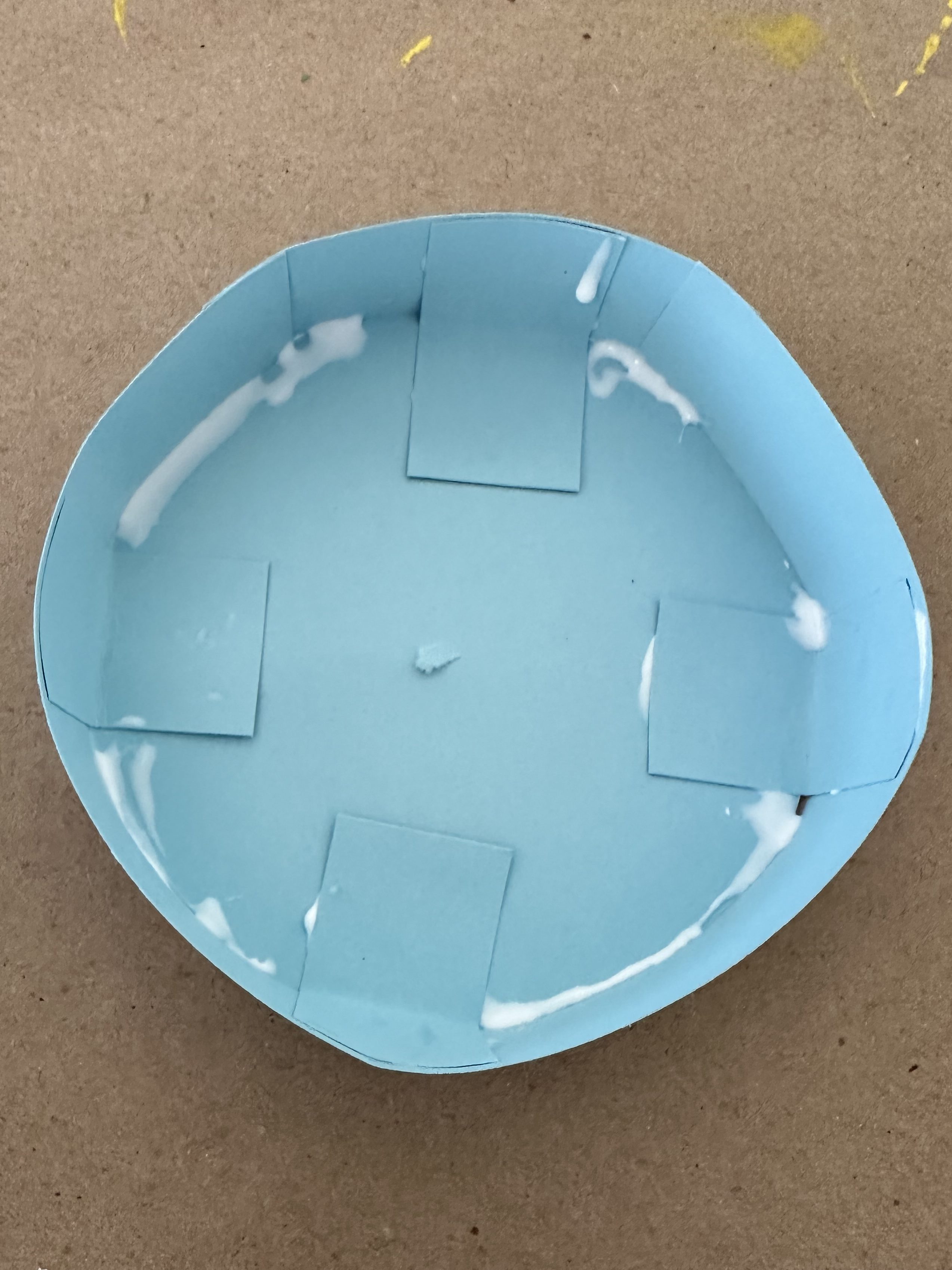 Close-up of a blue cardstock hat base with glue applied along the inside edge.