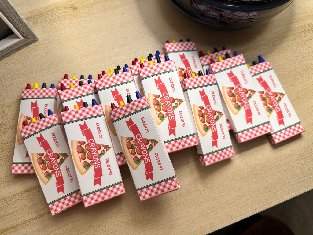 Custom Bubba’s Pizzeria crayon boxes filled with crayons, ready for table settings.