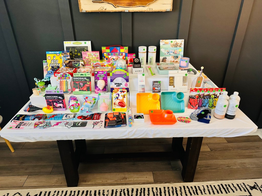 Display table full of colorful gift shop items like puzzles, art kits, bubbles, socks, and cookbooks.