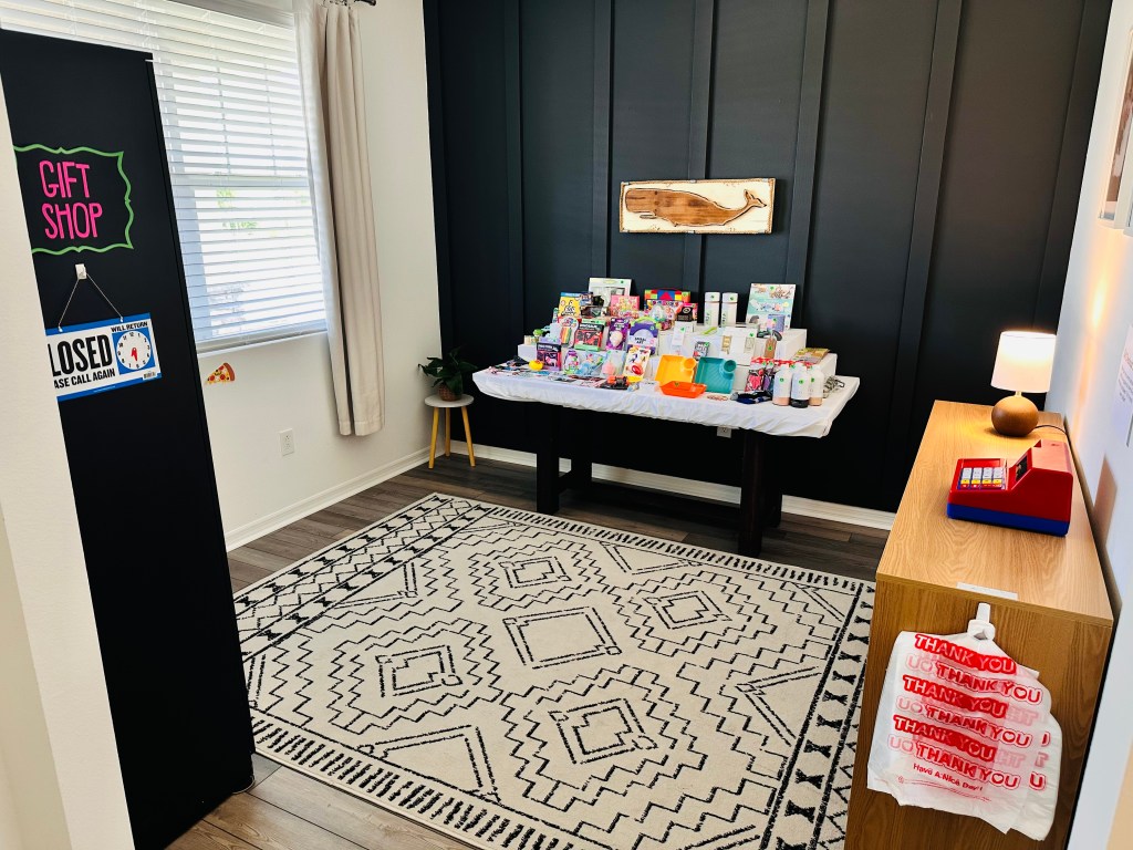 Wide view of Bubba’s Pizzeria gift shop with a table full of prizes, a toy cash register, and a “Gift Shop” sign at the entrance.