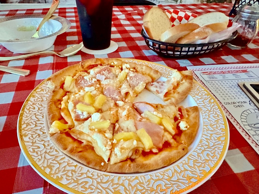 Hawaiian pizza with ham, pineapple, and cheese served on a plate at Bubba’s Pizzeria party.