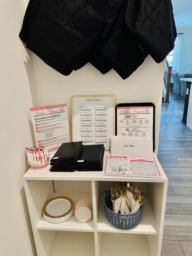 Full view of Kitchen Station #1 with aprons hanging, name tags on a board, and supplies laid out.