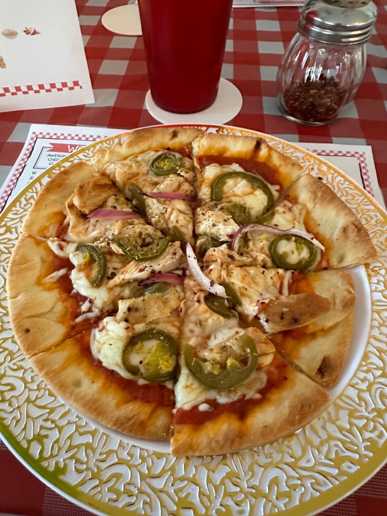 A sliced pizza served on a decorative plate at the dining table during Bubba’s Pizzeria party.