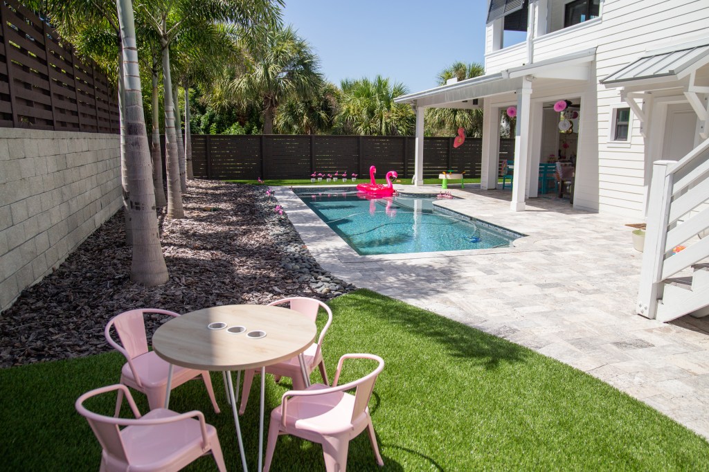 Backyard pool decorated with flamingo floats and a nearby child-sized pink table set