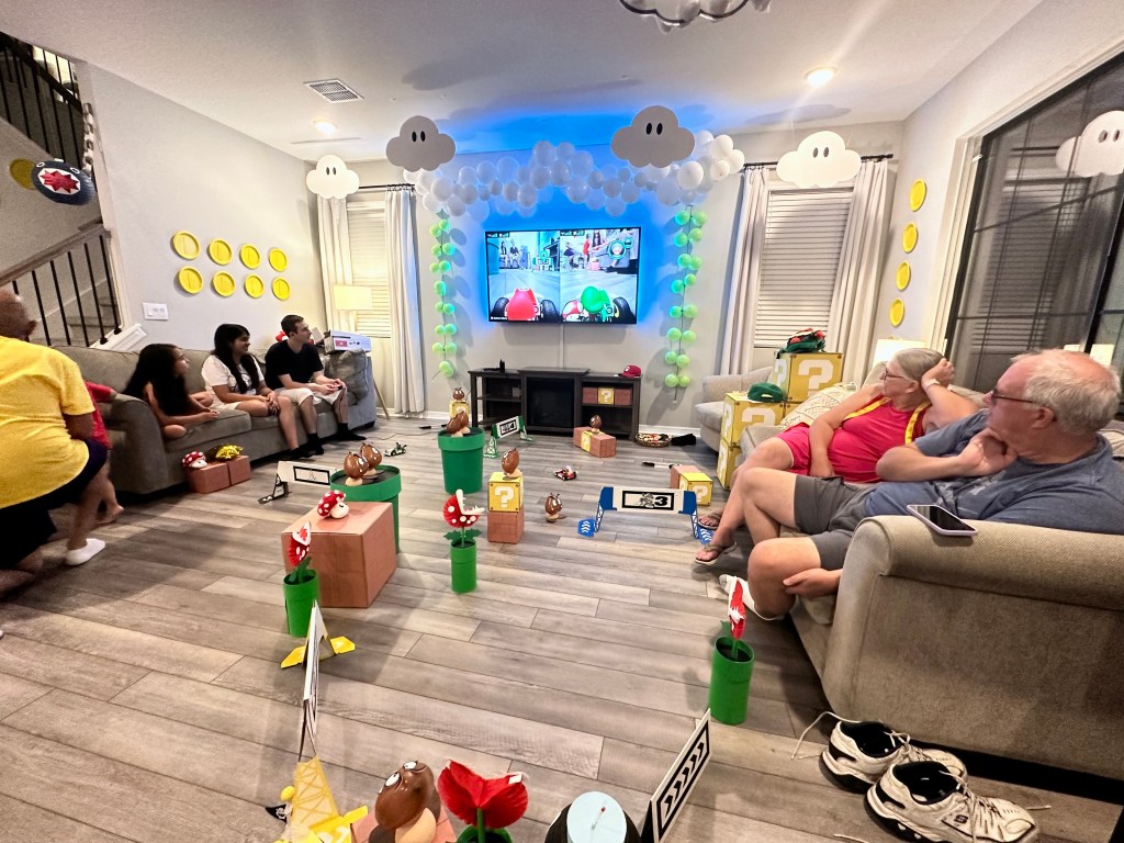 Living room transformed into a Mario Kart race course with balloon clouds, question blocks, Goombas, and Piranha Plants for a Mario Kart Live Home Circuit game.