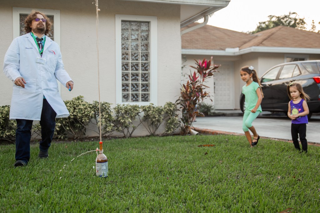 Elsa and Mallory react with wide eyes as a Mentos and Diet Cola fountain shoots into the air.