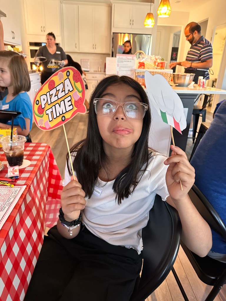 A child sticking out her tongue for a photo in Bubba's Pizzeria with pizza-themed signs.