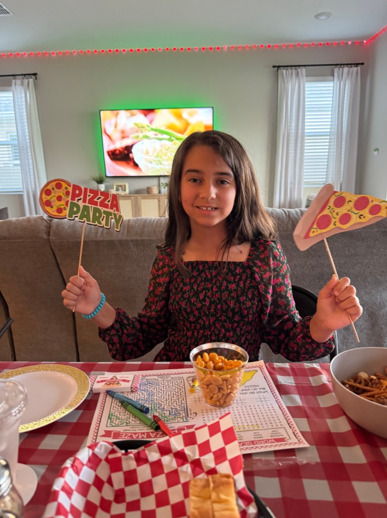 A girl posing with pizza photo booth props while snacking on appetizers.