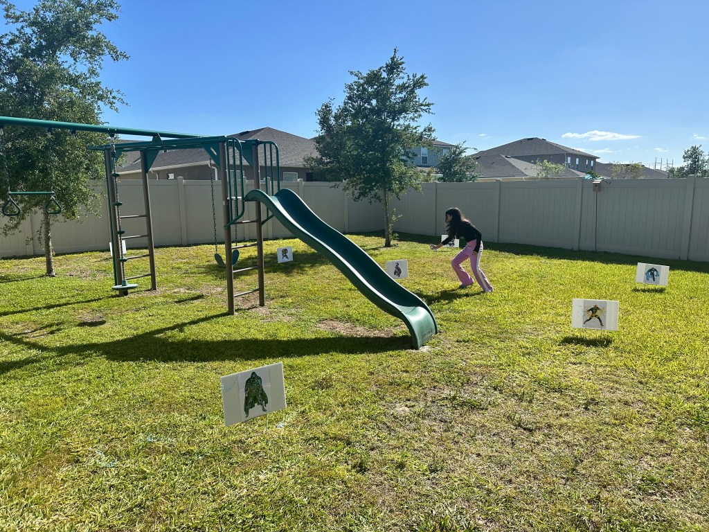 Backyard setup for Spider-Man villain target practice with laminated villain yard signs spaced around the grass.