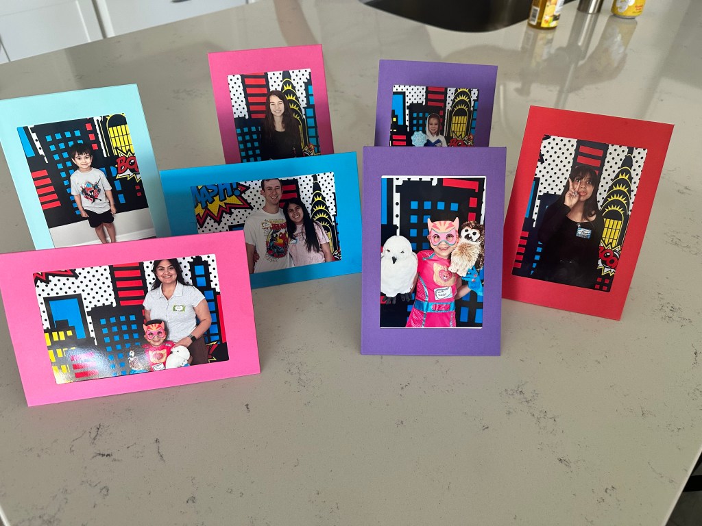 Printed photo booth pictures displayed in colorful cardstock frames from a Spider-Man birthday party.
