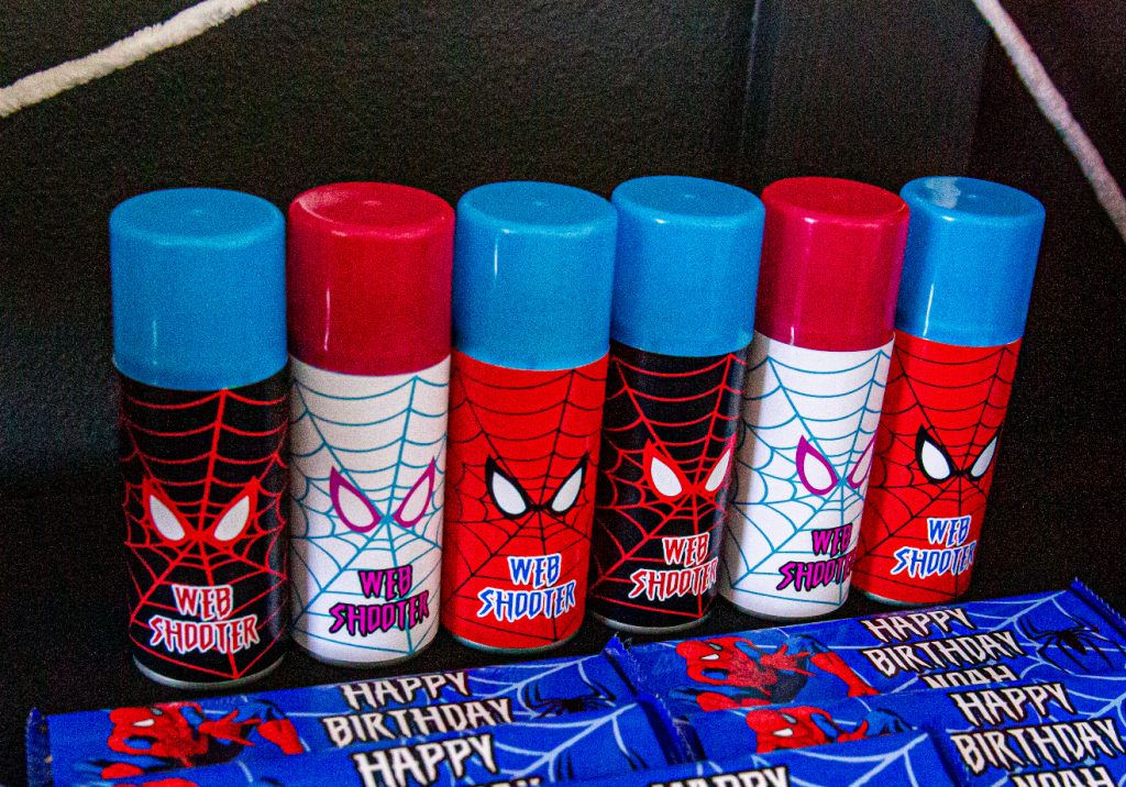 Row of red, black, and white silly string cans wrapped in Spider-Man web-shooter labels.