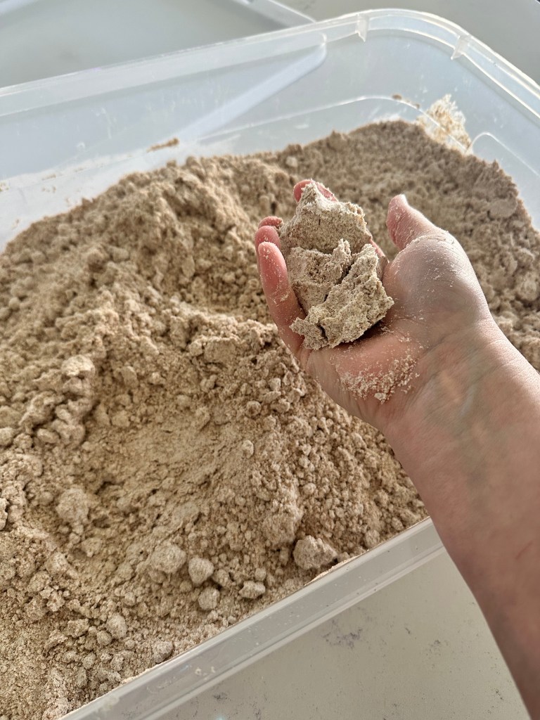 Close-up of oil and flour sand mixture in hand, showing the texture for the treasure dig game.