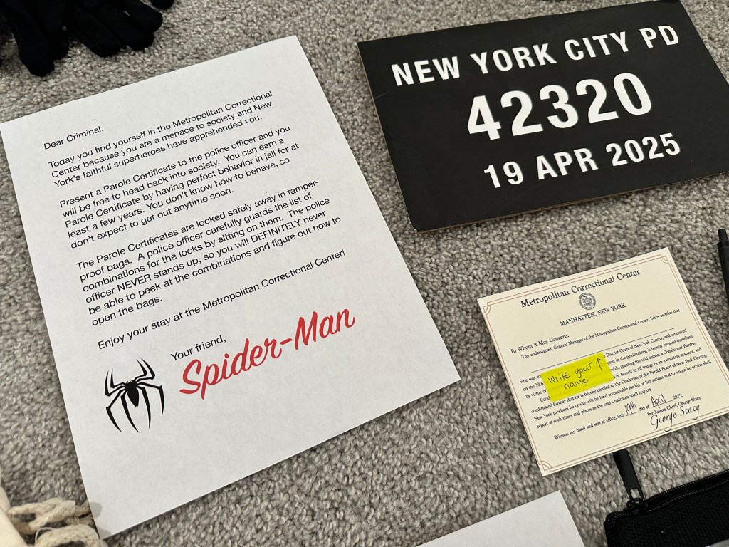Close-up of Spider-Man’s jail instructions, a mugshot sign, and a printed parole certificate for the Superheroes vs. Robbers party game.
