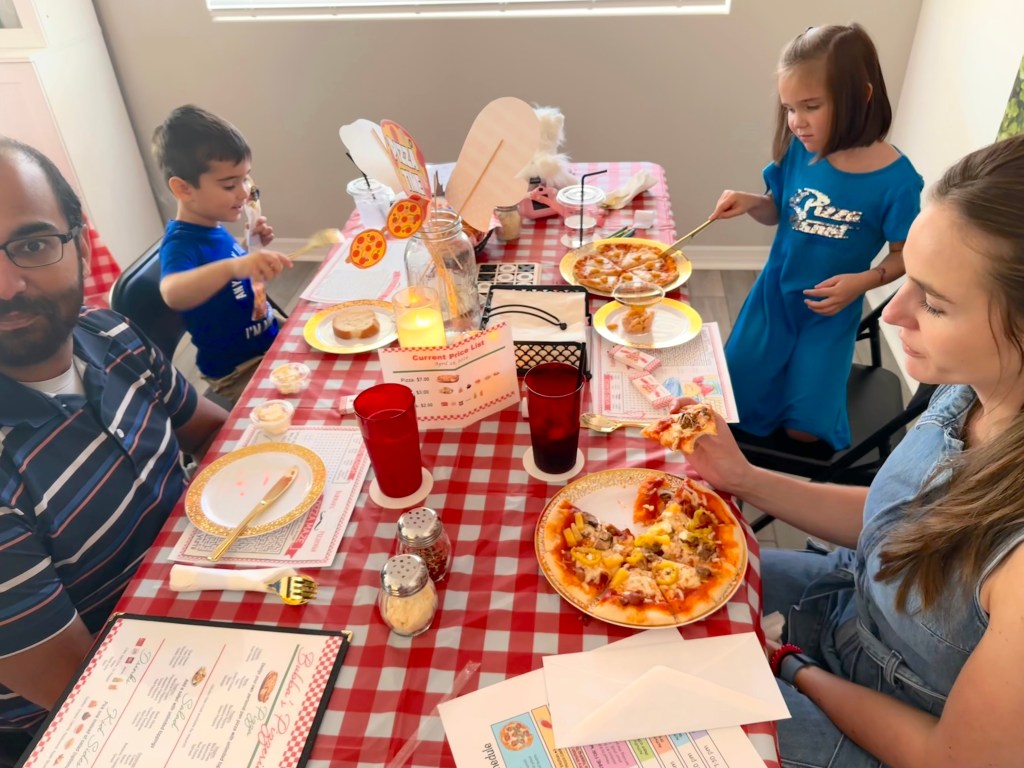 Guests at Bubba’s Pizzeria enjoying their made-to-order pizzas at a red‑check table.