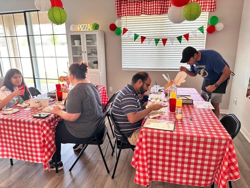 Two tables of diners eating while a server checks in during the rotating restaurant schedule.
