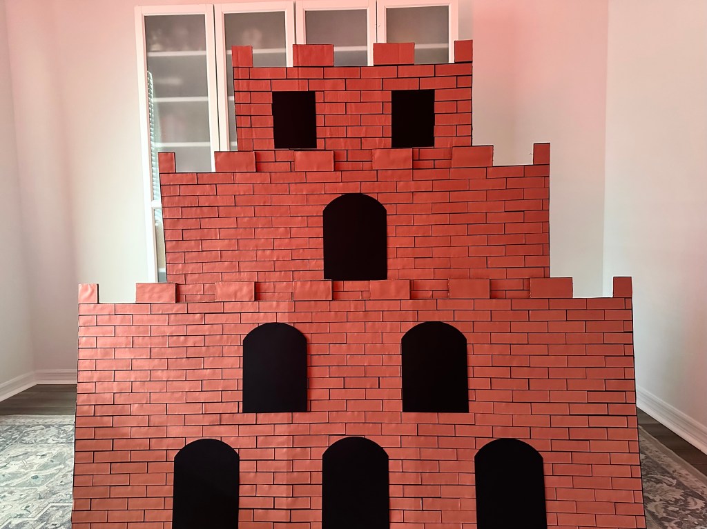 Large DIY Bowser’s Castle prop made of cardboard and decorated to resemble a Mario video game castle for a Super Mario birthday party backdrop.