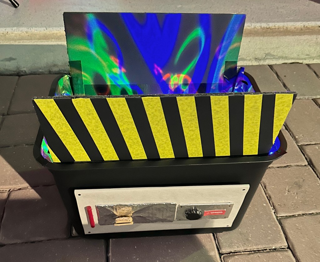 Homemade glowing Ghostbusters ghost trap prop with LED lights and striped caution lid on Halloween night.