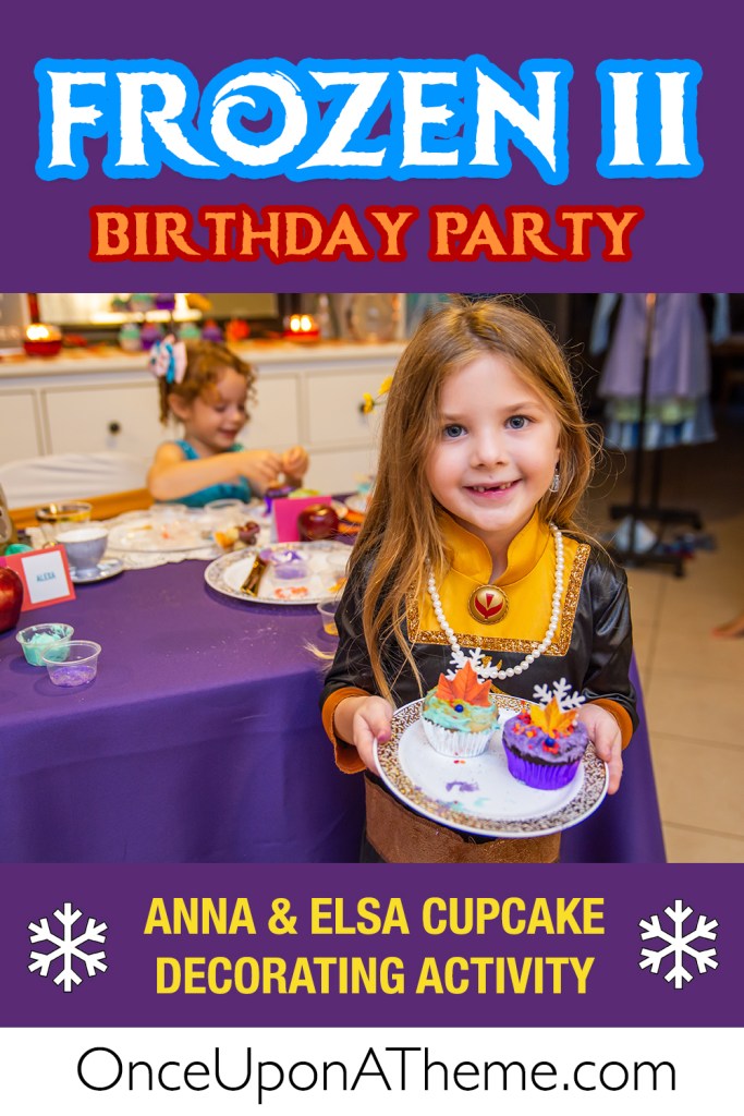Young girl in an Anna costume smiles while holding two cupcakes she decorated with edible fall leaves and snowflakes during a Frozen II-themed birthday party