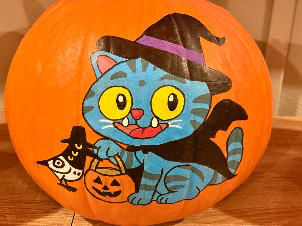 A painted Halloween pumpkin showing Derpy Tiger dressed as a witch, holding a jack-o’-lantern, with Sussie the bird perched beside him.