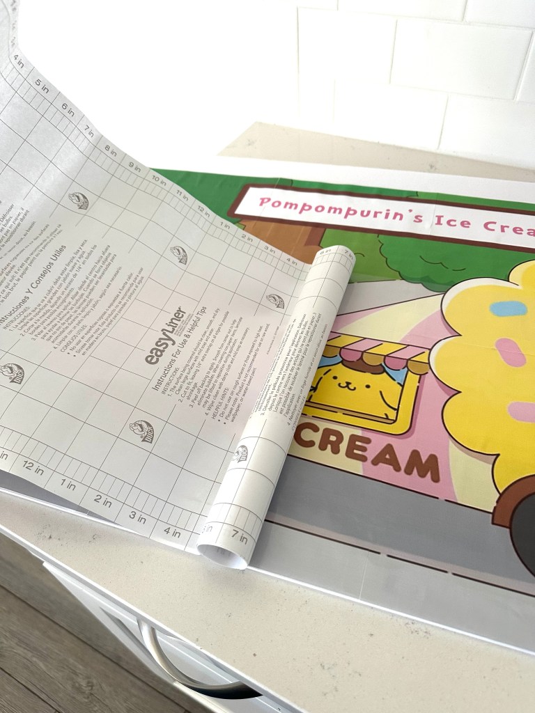 Clear contact paper being applied over the finished sign to add a glossy finish and protect the surface.