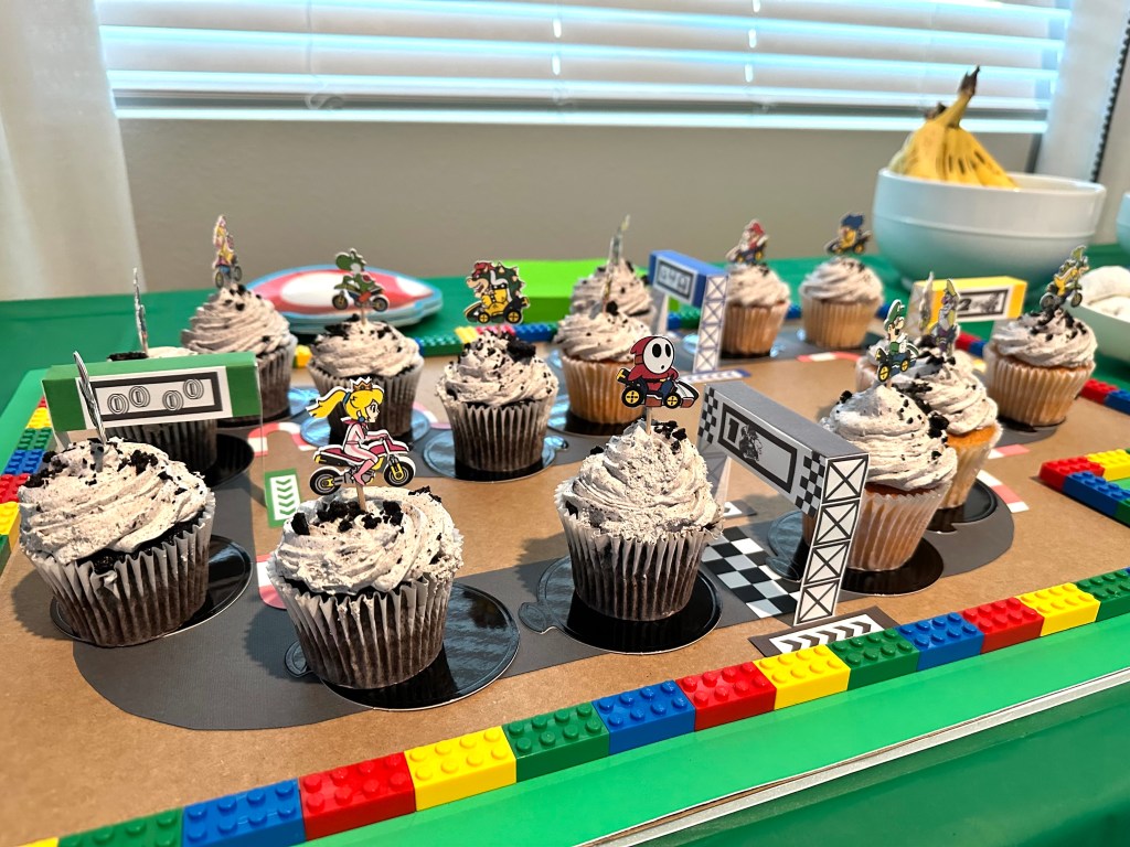 Mario Kart cupcake race track centerpiece made from LEGO bricks and cupcake toppers featuring Mario characters, perfect for a Super Mario birthday party.