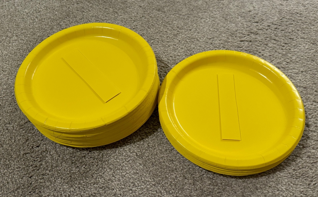 DIY Mario party coin decorations made from yellow paper plates and cardstock strips attached with foam stickers for a 3D effect.
