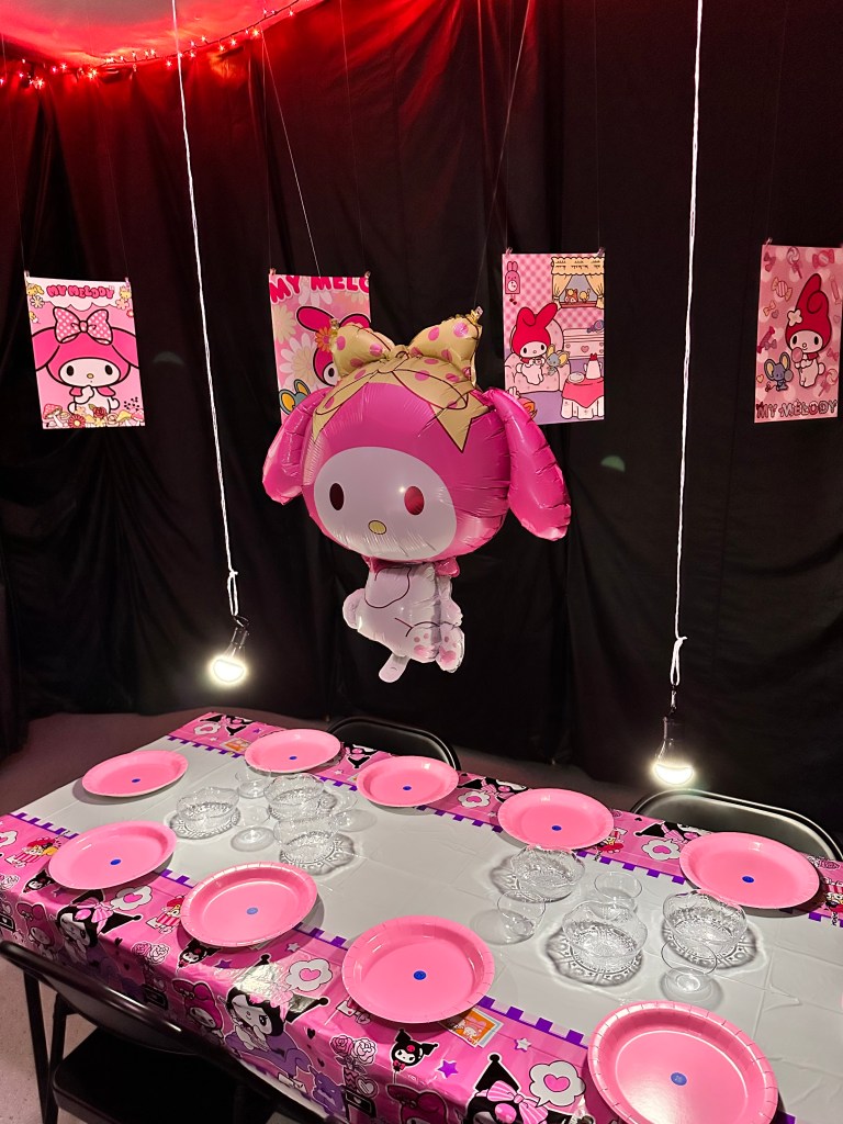 Close view of the My Melody table with pink plates, topping bowls, and a My Melody balloon surrounded by themed posters.