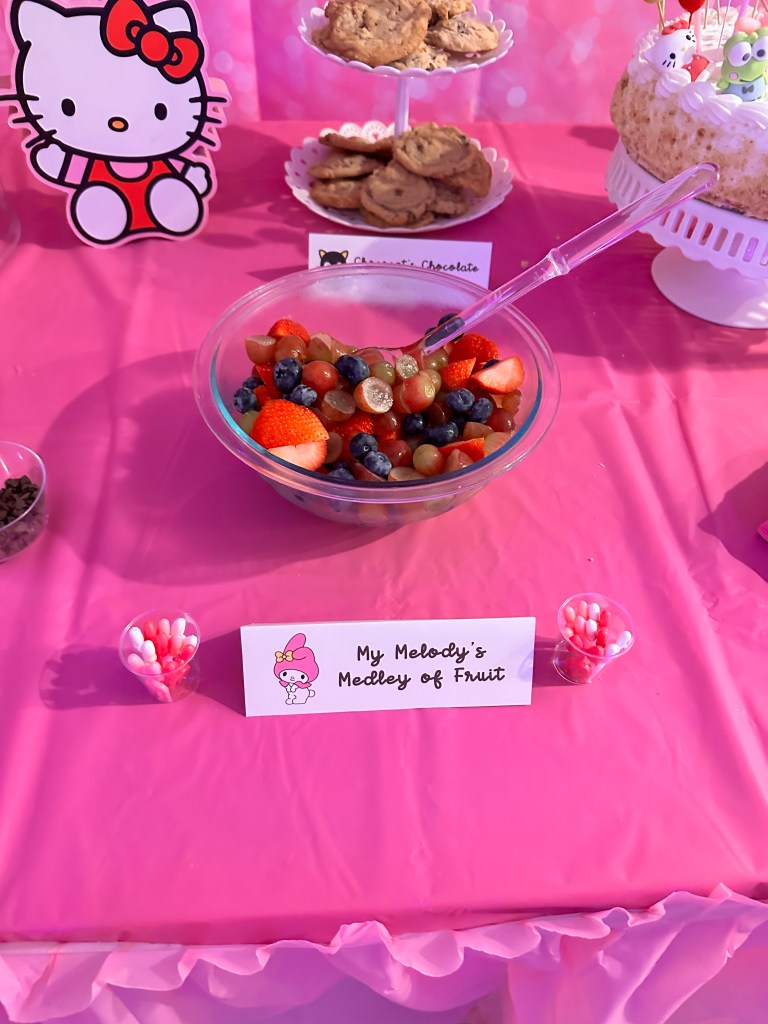 Fruit salad with themed bow-topped picks labeled as My Melody’s Medley of Fruit
