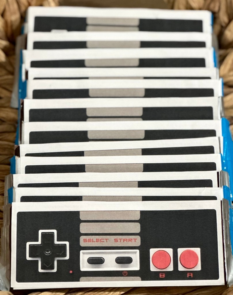 DIY Nintendo controller candy bar party favors displayed on a table, wrapped to look like classic Nintendo controllers for a Super Mario birthday party.